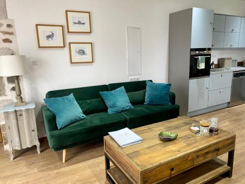 sala de estar con sofá verde y mesa en La Petite Grange Gite, en Oradour-Fanais