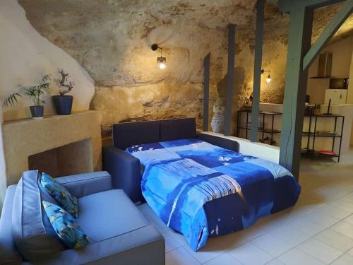 a bedroom with a blue bed and a couch at Maison troglodytique Doué La Fontaine in Doué-la-Fontaine