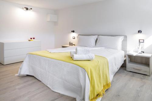 una camera bianca con un grande letto con una coperta gialla di Bandiera 68 Apartment a Cagliari