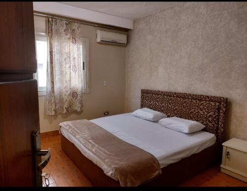 um quarto com uma cama grande com lençóis brancos e uma janela em Family residence in the best location no Cairo