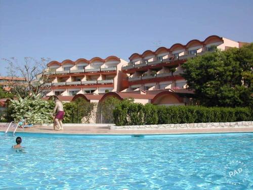 une personne dans une piscine en face d'un hôtel dans l'établissement 2 Pièces Climatisé-WIFI / 4 voyageurs / Boxe Privé / 2 piscines / 2 tennis / Pétanque / PingPong, à Antibes