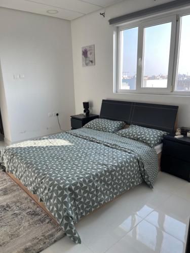a bedroom with a bed and two windows at Al Qalah flats 