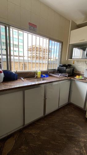 an empty kitchen with a counter and some windows at Rota BH Hostel in Belo Horizonte