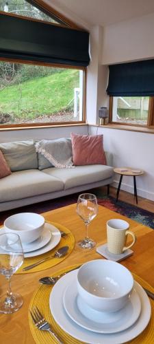 a table with plates and glasses and a couch at The Glasshouse in Ilfracombe