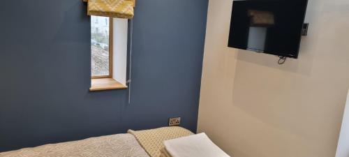 a room with a tv and a bed and a window at The Glasshouse in Ilfracombe