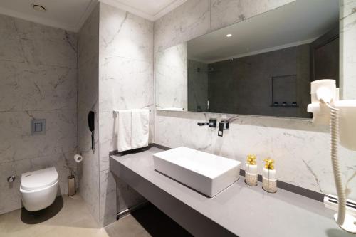 a bathroom with a sink and a toilet and a mirror at Hotel Pia Bella in Kérynia