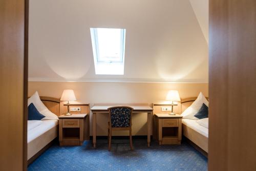 a room with two beds and a desk and a window at AKZENT Hotel Bayerwald-Residenz in Neukirchen