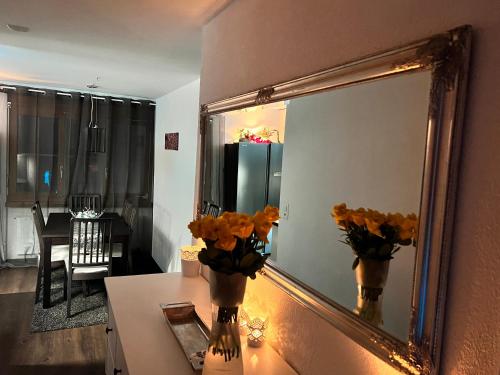 a mirror on a wall next to a table with flowers at Casa Ucliva - Charming Alpine Apartment Getaway in the Heart of the Swiss Alps in Rueras