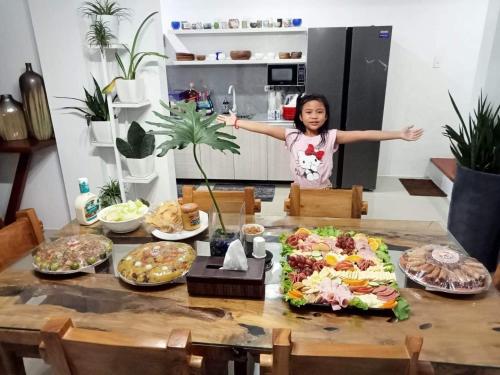 Una joven parada detrás de una mesa con comida. en Natalie's Villa, en Iloilo City