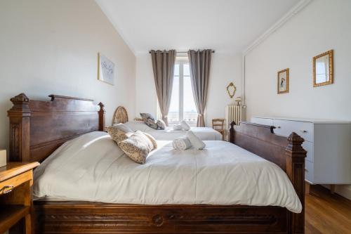 - une chambre avec un grand lit en bois et des draps blancs dans l'établissement LA SUITE MARCELLIN - Magnifique T3 avec garage et balcon Lyon 7, à Lyon