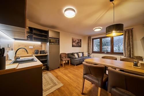 a kitchen and living room with a table and a couch at Vlčí Stopa Apartments in Pec pod Sněžkou