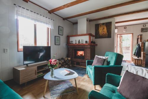 a living room with a tv and a fireplace at Jarzębinowa - Dom do wynajęcia na Podlasiu in Łuka