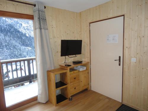 een kamer met een deur, een televisie en een raam bij Orelle 3 Vallées - 2 pièces 4 personnes in Orelle