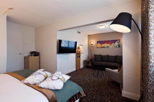 a hotel room with a bed and a living room at Mercure Lyon Charbonnières in Charbonnières-les-Bains