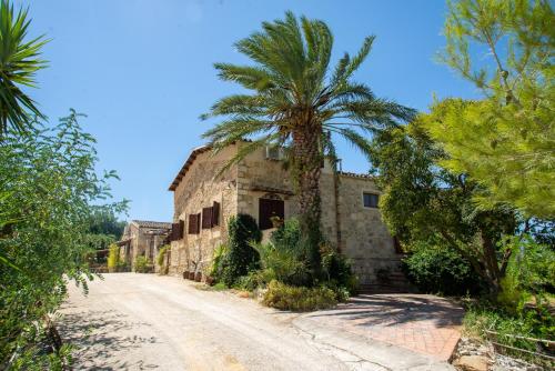 un vieux bâtiment en pierre avec un palmier sur un chemin de terre dans l'établissement Agriturismo Casalicchio, à Cammarata