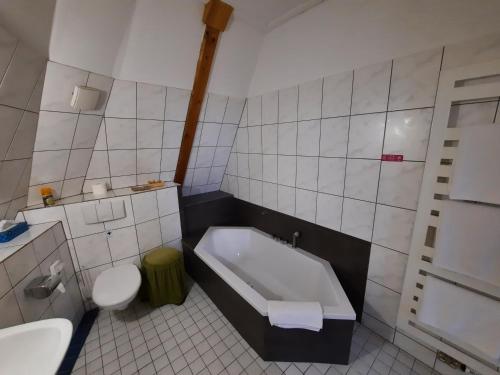 a bathroom with a tub and a toilet and a sink at Hotel Koruna in Jeseník
