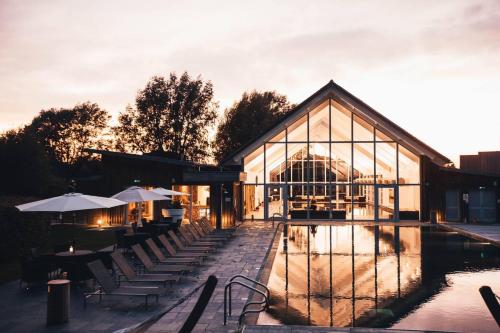 a building with tables and chairs next to a pool at Luxurious Lakefront Home with Pool/Spa Access in Cirencester