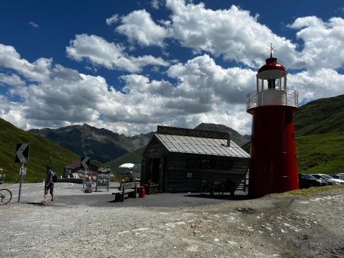 a red lighthouse in front of a small building at Casa Ucliva - Charming Alpine Apartment Getaway in the Heart of the Swiss Alps in Rueras