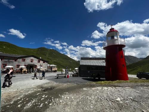 a red and white lighthouse next to a building at Casa Ucliva - Charming Alpine Apartment Getaway in the Heart of the Swiss Alps in Rueras