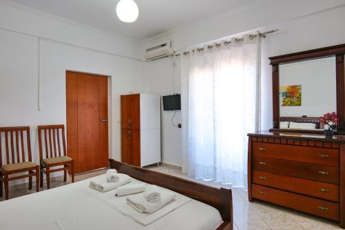Schlafzimmer mit einem Bett, einer Kommode und einem Spiegel in der Unterkunft Guest House Gerard in Ksamil