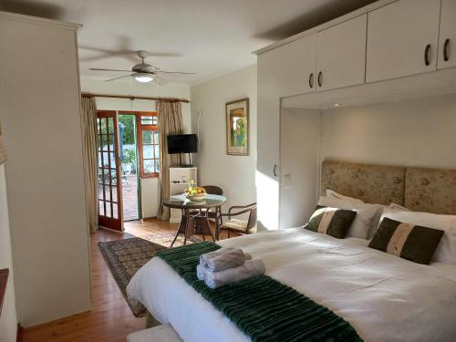 1 dormitorio con 1 cama grande y 1 mesa en Wine Route 44 Guesthouse en Somerset West