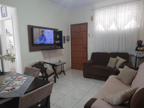 a living room with a couch and a tv on the wall at Apartamento Central, oitavo andar in Serra Negra