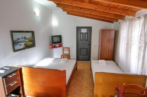 a room with two beds and a desk and a tv at Guest House Gerard in Ksamil