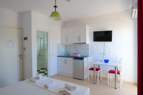 a kitchen with white cabinets and a table and chairs at Guest House Gerard in Ksamil