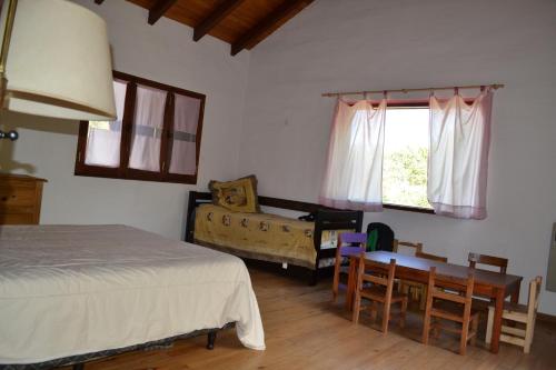 1 dormitorio con 1 cama, mesa y sillas en Atardecida en Villa Las Rosas