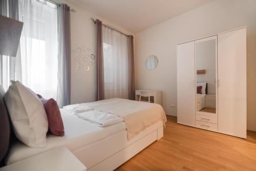 - une chambre blanche avec un lit et un grand miroir dans l'établissement An der Donau, 10 Minuten ins Zentrum, Klimaanlage, à Vienne
