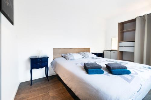 a bedroom with a large bed with two blue pillows at LE CÔTÉ COUR in Rodez