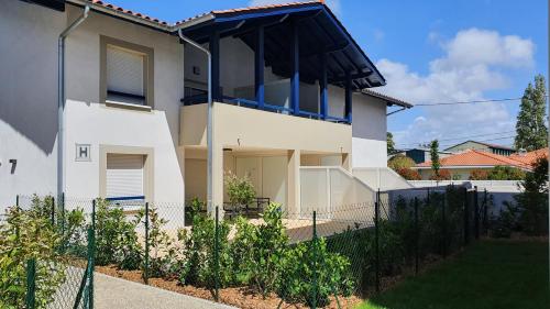 une maison blanche avec une clôture devant elle dans l'établissement T2 NEUF ANGLET CENTRE - BIARRITZ, à Anglet