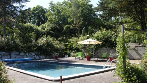 a swimming pool with an umbrella and a table and chairs at Château de Cartou in Durfort
