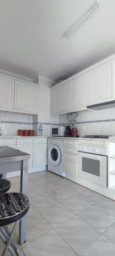 a kitchen with white cabinets and a washing machine at Quarteira Beach in Quarteira