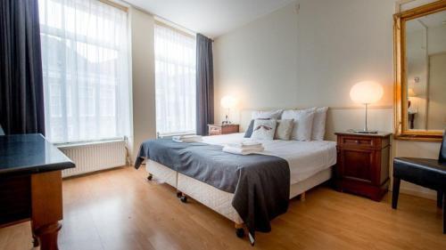 een slaapkamer met een groot bed en een spiegel bij Hotel de Wijnberg in Bolsward