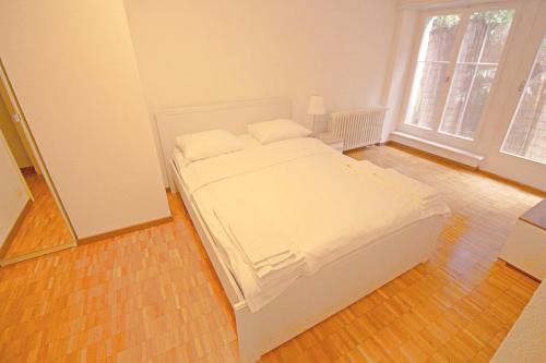 a bedroom with a white bed and a large window at Swiss Star Basel Schweizergasse - Self Check-In in Basel