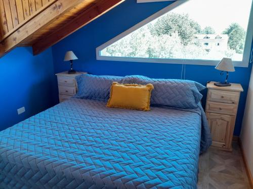 1 dormitorio con paredes azules y 1 cama con almohada amarilla en Apart Hotel Pehuenia en Villa Pehuenia