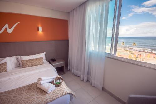 a bedroom with a bed and a view of the beach at Real Classic Bahia Hotel in Salvador