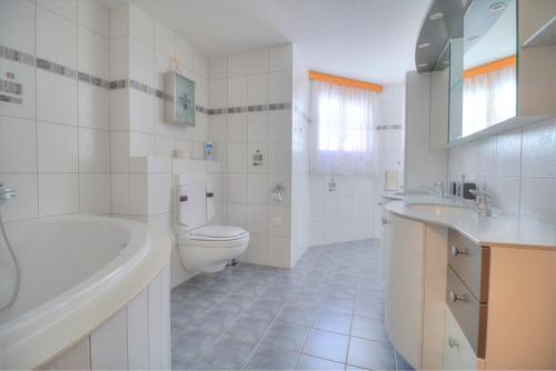 a bathroom with a toilet and a tub and a sink at Aramis 1 in Leukerbad