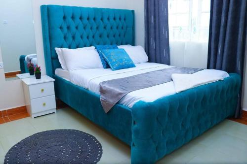 Una cama azul con cabecero azul en un dormitorio en The porch garden Estate 1 bedrm en Nairobi
