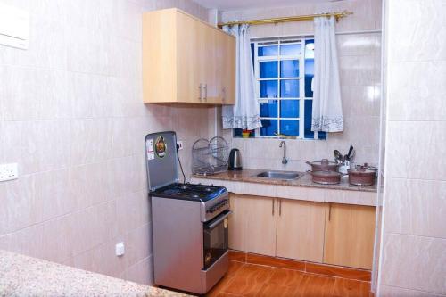 a small kitchen with a stove and a sink at The porch garden Estate 1 bedrm in Nairobi