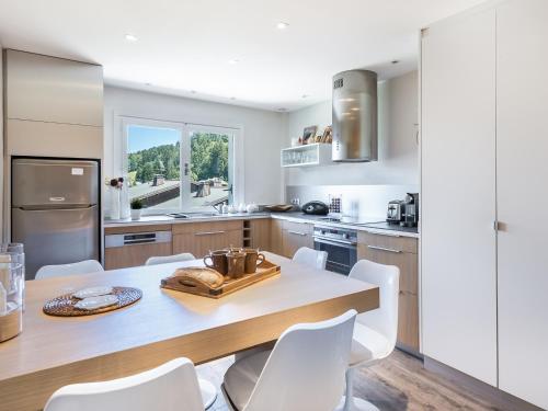 - une cuisine avec une table en bois et des chaises blanches dans l'établissement Appartement rénové 3 pièces, 6 pers, balcon, proche pistes et commerces, Megève Jaillet - FR-1-453-126, à Megève
