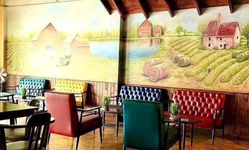 a restaurant with chairs and a mural of a farm at The Colored House Jomtien in Jomtien Beach