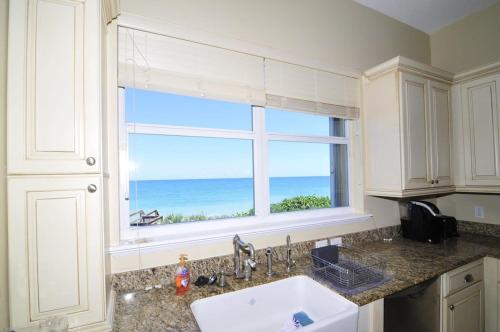 een keuken met een raam met uitzicht op de oceaan bij Pelican Perch-Four bedroom heated pool oceanfront home in Melbourne Beach
