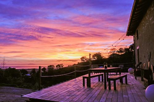 a table and bench on a deck with a sunset at Eco lodge Carbonaccio in Chiatra