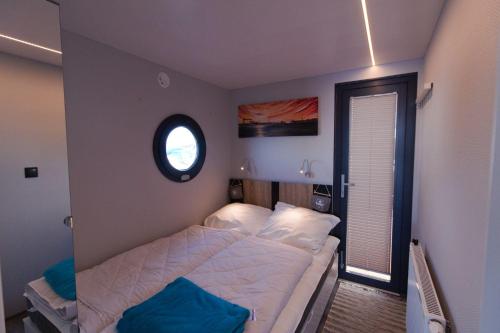 a small bedroom with a bed and a window at Hausboot Fjord Lacerta mit Dachterrasse in Wendtorf in Wendtorf