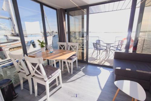 ein Esszimmer mit einem Tisch, Stühlen und Fenstern in der Unterkunft Hausboot Fjord Lacerta mit Dachterrasse in Wendtorf in Wendtorf