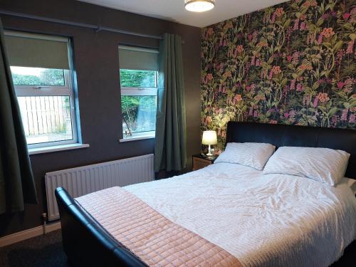 una camera da letto con un grande letto e carta da parati floreale di Braeside B&B a Bushmills
