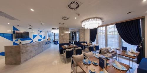 a restaurant with tables and chairs and a chandelier at Hotel Foldana in Budapest