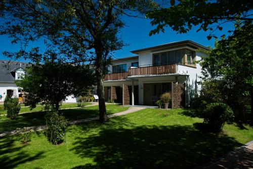 een huis met een balkon op een gazon bij Aparthotel Friesenhof in Wenningstedt